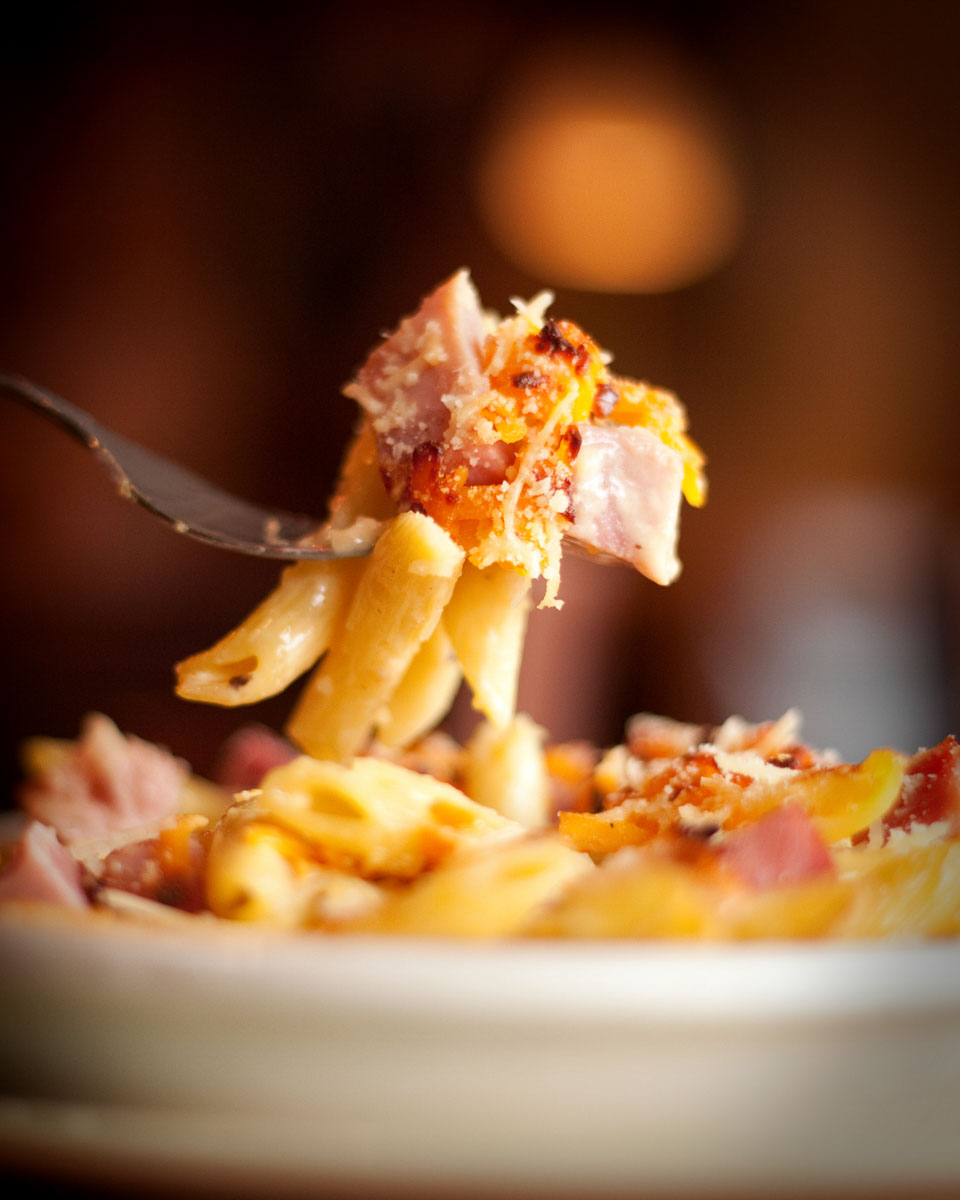 fork holding up loaded Mac and cheese with bacon