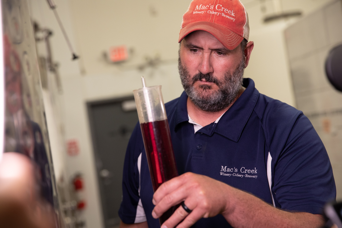 A vintner checking levels on hydrometer
