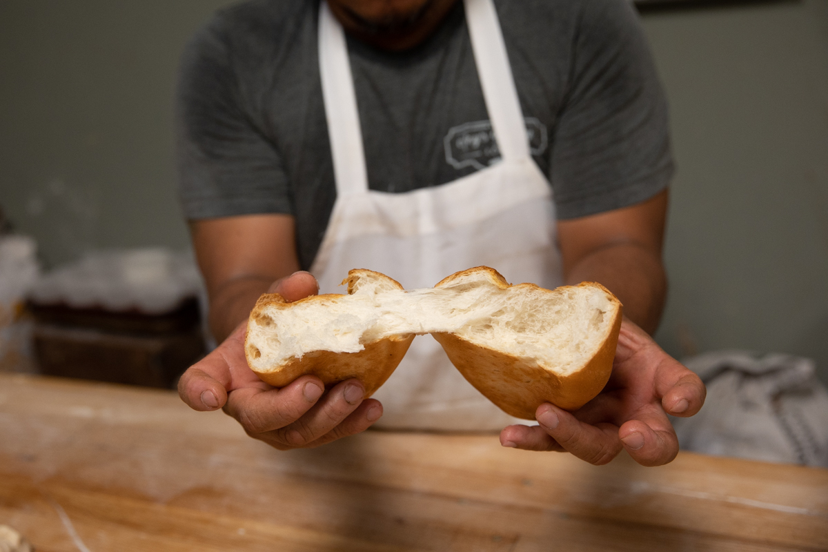 baker splitting fresh roll with hands