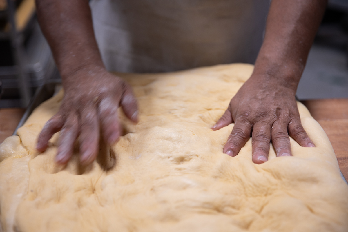Baker kneading the large piece of dough.