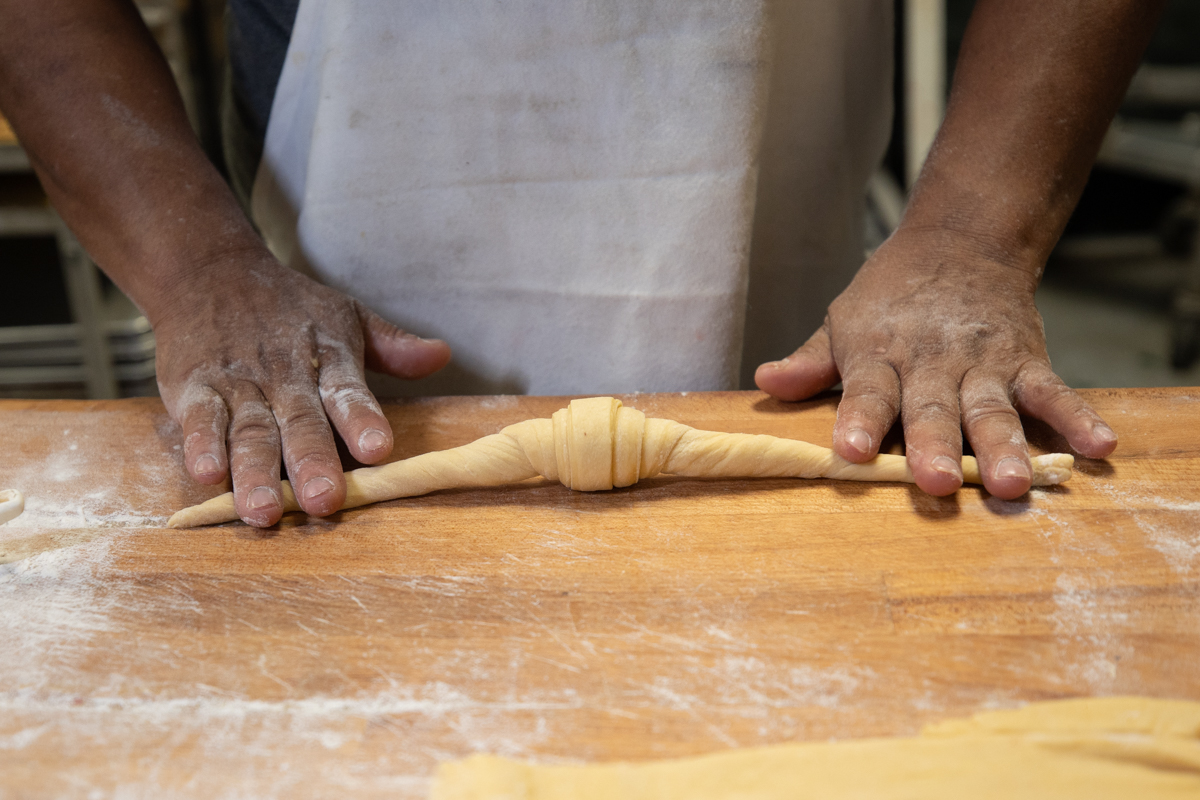 baker hand rolling croissants