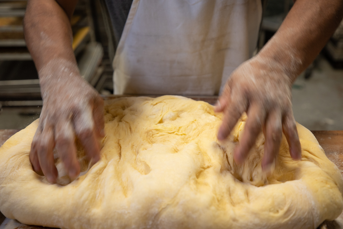 Baker kneading the large piece of dough.